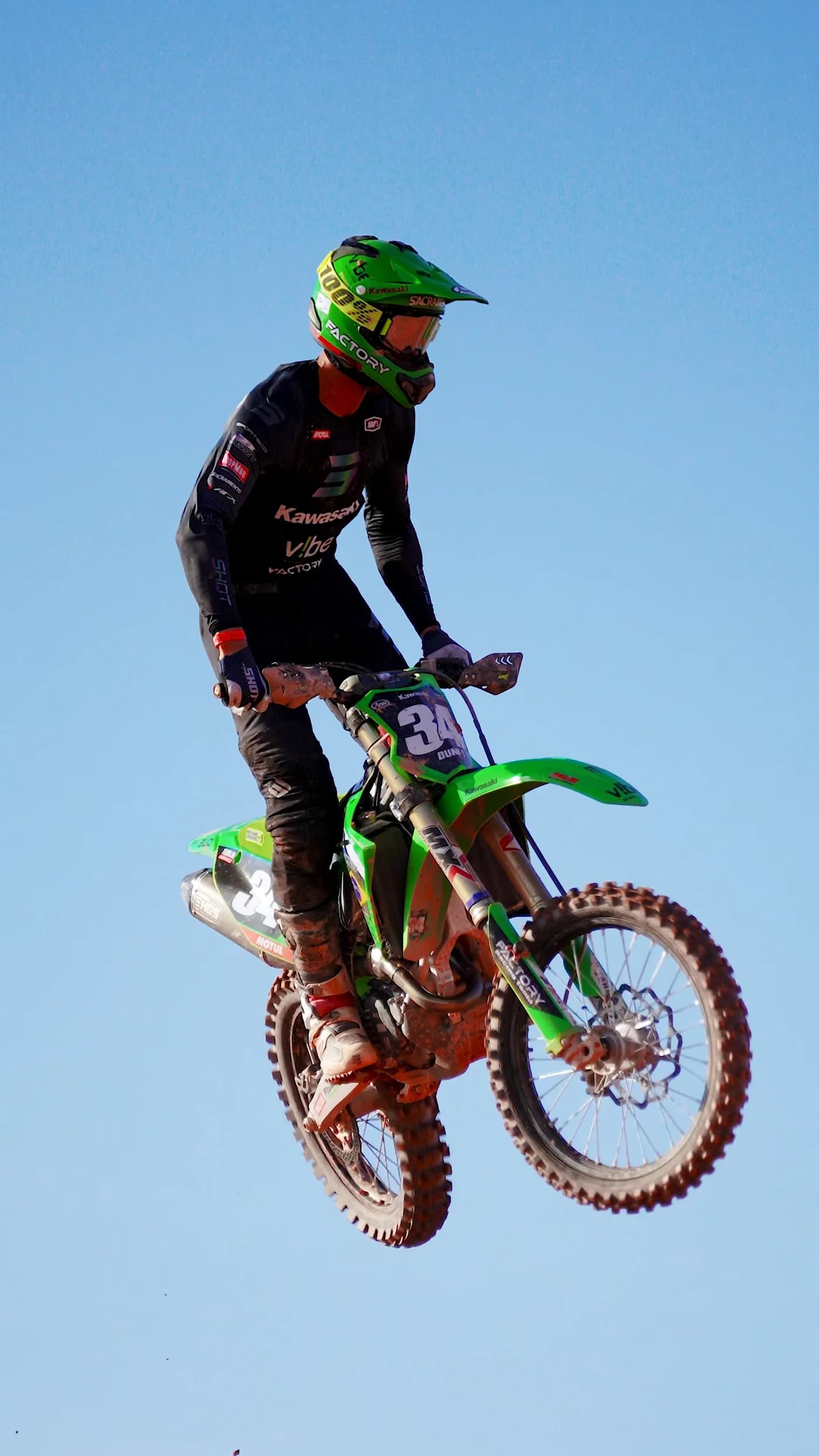 Piloto de motocross saltando com sua moto verde